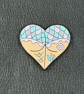 Booty-Herz-Siren_Detail Emaille-Pin Booty Herz Siren's Secret mit Meerjungfrauen-Schuppen und Muschel-Motiv in Türkis und Hautfarben